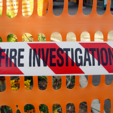 Fire investigation tape on an orange barrier fence